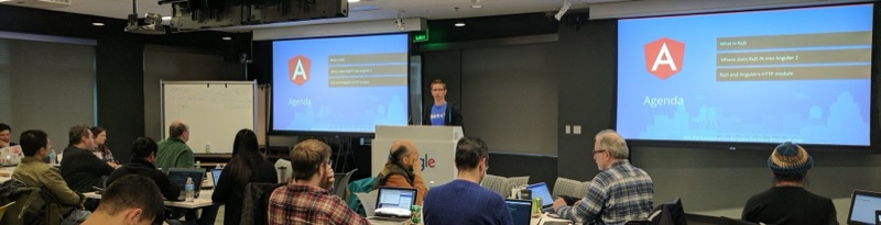 Panorama of Duncan at a lectern in a Google room, two screens showing the Angular logo and an RxJS agenda.